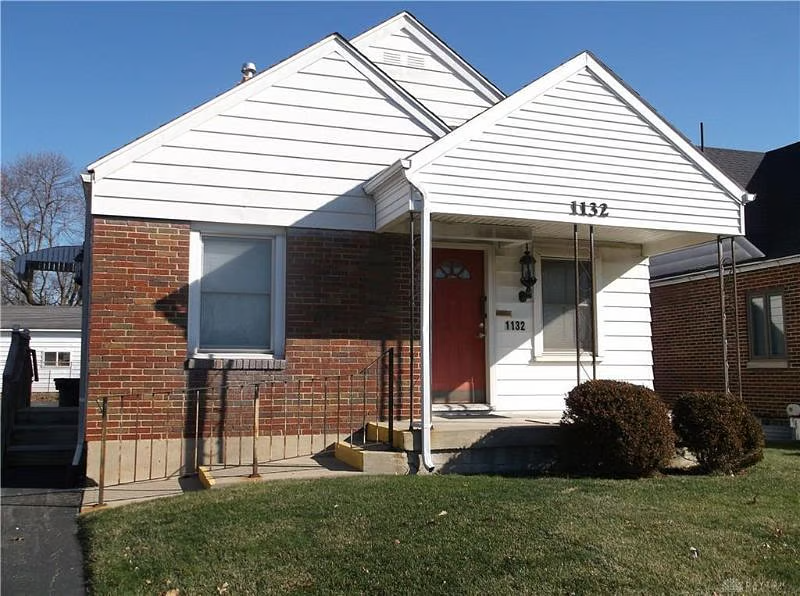 Brick single-story home with covered front porch and red door