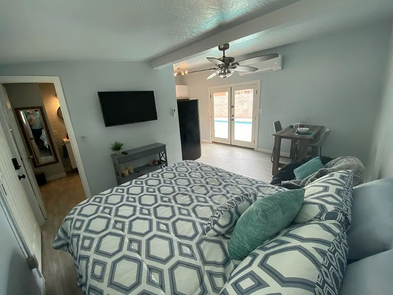 Guest suite bedroom with kitchenette and doors to the pool patio