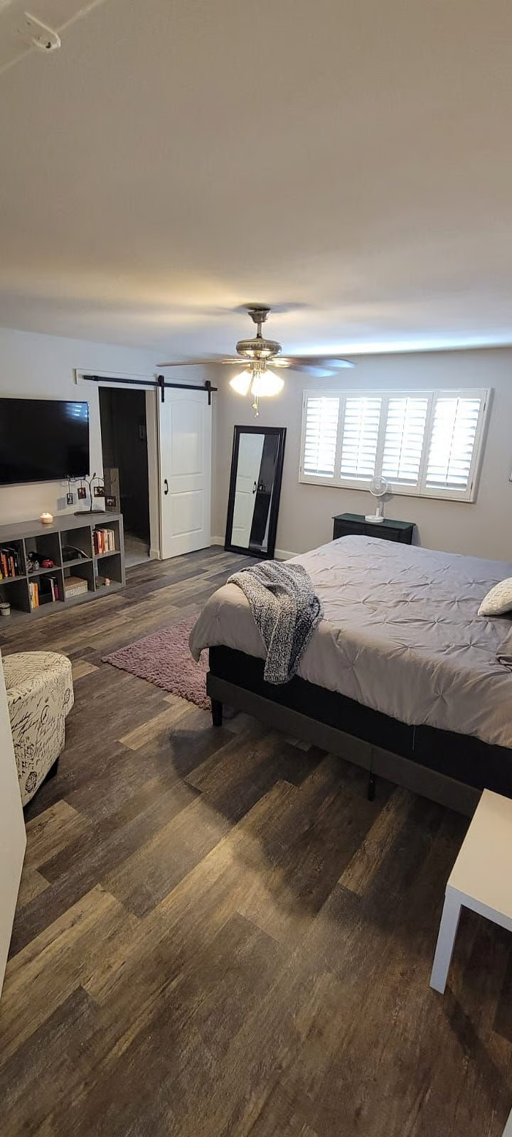 Spacious primary bedroom with barn door, TV wall and full-length mirror